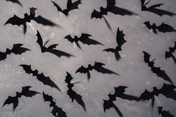 halloween, decoration and scary concept - black bats flying over grey background