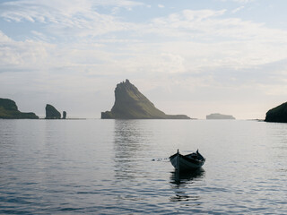 Boat on water with island Tindh&oacute;lmur in background, Faroe Islands.