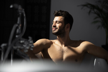 Close up shot of handsome man with beard in bathtub