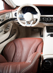 Modern luxury car Interior - steering wheel, shift lever and dashboard. Car interior luxury. Beige comfortable seats, steering wheel, dashboard, speedometer, display. Red and white perforated leather.