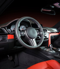 Modern luxury car Interior - steering wheel, shift lever and dashboard. Car interior luxury inside. Steering wheel, dashboard, speedometer, display. Red and black leather cockpit