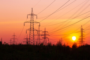 Fototapeta premium Electric power transmission lines. High voltage post. Industrial landscape. Electricity pylon at sunset sky on the background. Electric distribution station