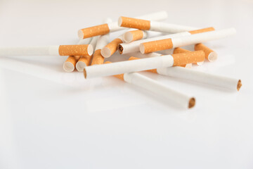 Cigarettes with a yellow filter lie on a white surface