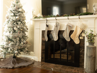 Decorated Christmas tree next to fireplace where four stockings are hung awaiting Christmas morning.