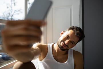 Top view of man sitting on windowsill and making selfie