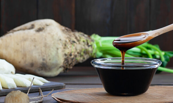 Sugar beet molasses in glass bowl with fresh sugar beetroot plant, healthy food, beta vulgaris