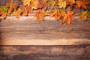 Obraz premium Autumn leaves over a textured vintage rustic wooden background with copy space