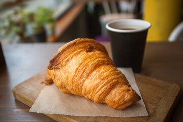 Delicious freshly baked croissant and coffee on a wooden background on the table. Great Breakfast in the morning. Rustic style.