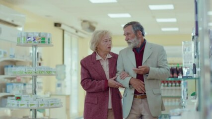 Close up sick old man with wife couple walking on drugstore. Feel headache. Conversation pharmaceutical client. Seller commercial health care buyer uniform. Slow motion