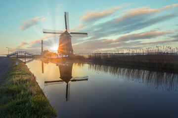 The De Kaagmolen windmill in front of a channel and boat, North Holland, Netherlands