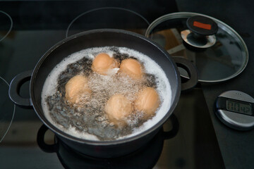 Fünf Bio Frühstückseier, Hühnereier kochen im Wasserbad	