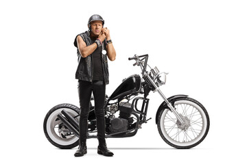 Fototapeta na wymiar Full length portrait of a biker with a chopper putting on a helmet