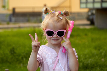 fashionable little girl in pink on a green grass background