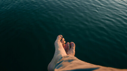 Feet dangling over the water with soft waves