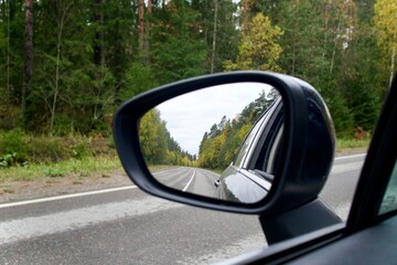 sideview, rearview mirror of a car on road at autumn or summer day at countryside