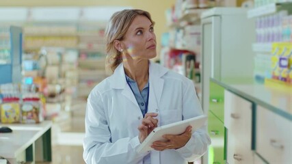Portrait woman in uniform pharmacist at pharmacy walking look around hold tablet computer check pills . Diagnosis young pharmaceutics store job healthy medicine. Slow motion