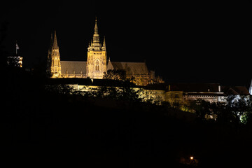 Fototapeta na wymiar illuminated Vitus Cathedral and Prague Castle at night in the center of Prague. and reflections of lights on the flowing river Vltava in the town