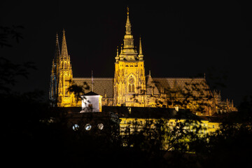 illuminated Vitus Cathedral and Prague Castle at night in the center of Prague. and reflections of lights on the flowing river Vltava in the town