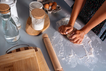 Unrecognized woman kneading the dough for bread with flour around on kitchen table. Homemade food concept. Food preparation. Cooking bread.
