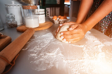Unrecognized woman kneading the dough for bread with flour around on kitchen table. Homemade food concept. Food preparation. Cooking bread.
