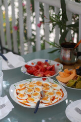 Boiled eggs with yoghurt sauce, tomato salda and various fruit on the breakfast table. Selective focus.