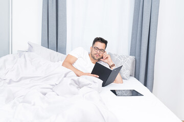 Young man reading a book on bed