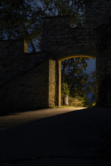 Obraz premium light from street lighting through the gate of the old wall from the 17th century in the center of Prague and a waste basket in a park in the Czech Republic at night