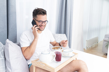 Young man on phone call having bed meal