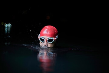 authentic triathlete swimmer having a break during hard training on night