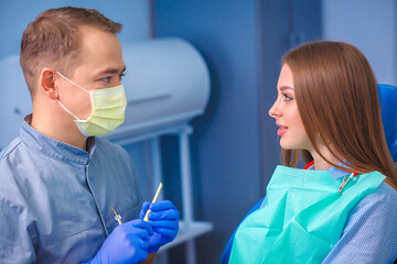 Young beautiful woman with beautiful white teeth sitting on a dental chair. Portrait of a woman with toothy smile sitting during examination at the dental office