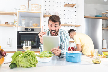 Two men cooking food using digital tablet in the kitchen