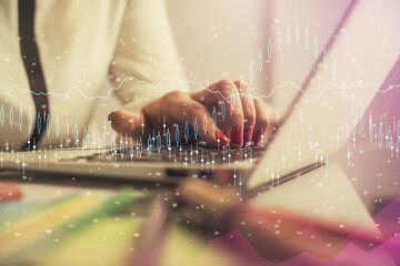 Double exposure of businesswoman hands typing on computer and financial graph hologram drawing. Stock market analysis concept.