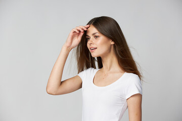 Obraz premium Beautiful woman holds her hands near her face and looks to the side in a white t-shirt 