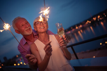 Happy senior couple celebrating with sparklers outdoor