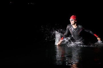 triathlon athlete finishing swimming training at dark night