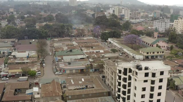  Drone video of city streets, transport, where you can see old houses, slums and the city center with skyscrapers against the backdrop of mountains in the clouds.Aerial shot of Arusha Tanzania.