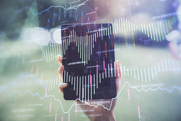 Double exposure of forex chart sketch hologram and woman holding and using a mobile device. Financial market concept.