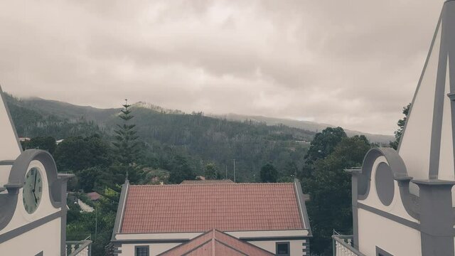 Cloudy sky over Prazeres church towers, Madeira. Aerial backward