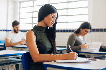 Young Brazilian university student sitting at her desk during class.