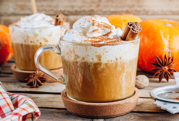 Pumpkin spiced latte or coffee in a glass on a vintage table. Autumn or winter hot drink.