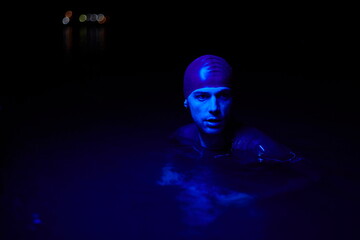 authentic triathlete swimmer having a break during hard training on night neon gel light