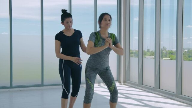 Exercise concept. Two fitness women doing squat exercise workout indoor. 4k Resolution.