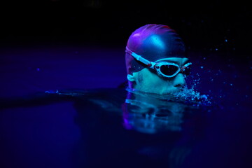 authentic triathlete swimmer having a break during hard training on night neon gel light
