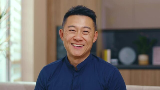 Portrait happy asian chinese man look at camera at home. Feel confident. Young japanese korean discussion casual relax face communication. Slow motion