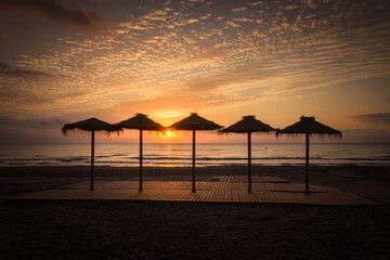 Colorful sunset among umbrellas on the beach