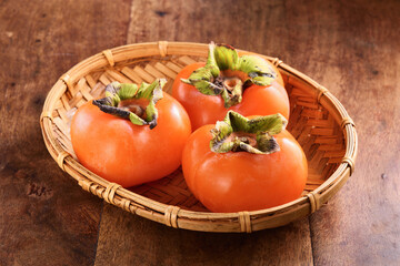 Delicious ripe persimmon fruit on bamboo basket 