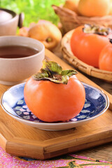 Delicious ripe persimmon fruit on wooden tray.  