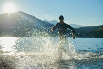 triathlon athlete starting swimming training on lake