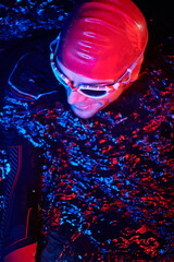 authentic triathlete swimmer having a break during hard training on night neon gel light