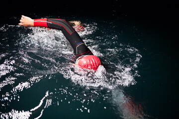 triathlon athlete swimming in dark night wearing wetsuit